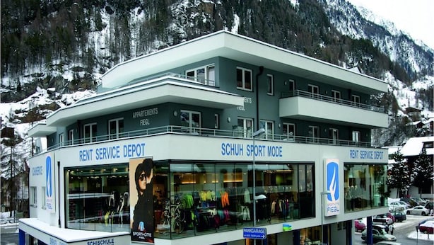 A multi-story building with a 'Rent Service Depot' and 'Schuh Sport Mode' signage, indicating a rental service area.