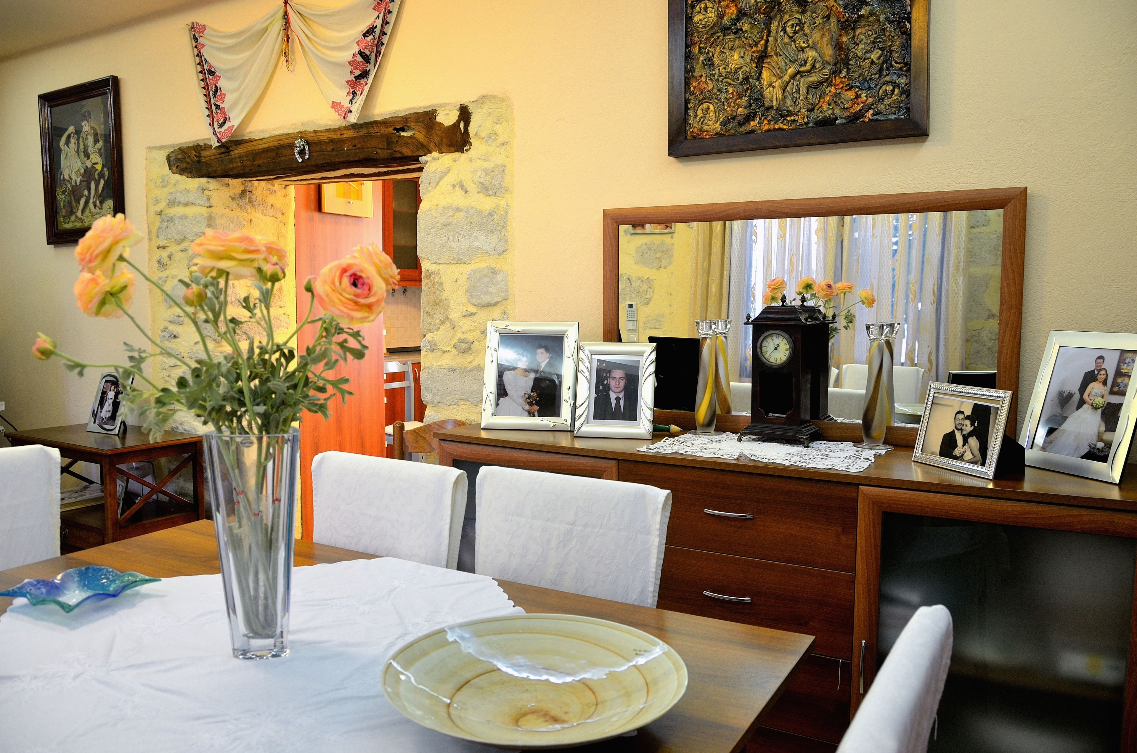 Un'area pranzo con tavolo in legno, sedie, un vaso con fiori, foto incorniciate, un orologio e uno specchio.