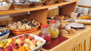 Une table de buffet proposant une variété d’aliments, notamment des fruits, des pâtisseries et des boissons.