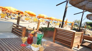 Une terrasse en bois avec une table dressée pour un repas, comprenant une boisson et des amuse-gueules.
