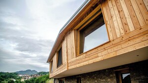 Un edificio moderno con paredes exteriores de madera, ventanas amplias y una vista de un pueblo al fondo.