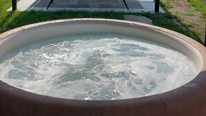 Un jacuzzi bajo una pérgola con vistas a una cabaña de madera y montañas.