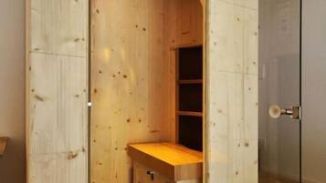 A wooden room with a built-in wardrobe, a small bench, and a door leading to another space.