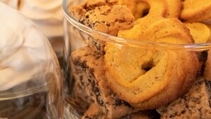 Un cuenco de vidrio lleno de galletas y un vaso de crema batida.