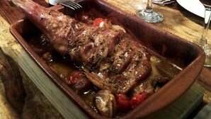 A roasted duck in a ceramic dish, a bottle of wine, and glasses of red wine on a wooden table. - Hotel La Tinensa (La Pobla de Benifassa)