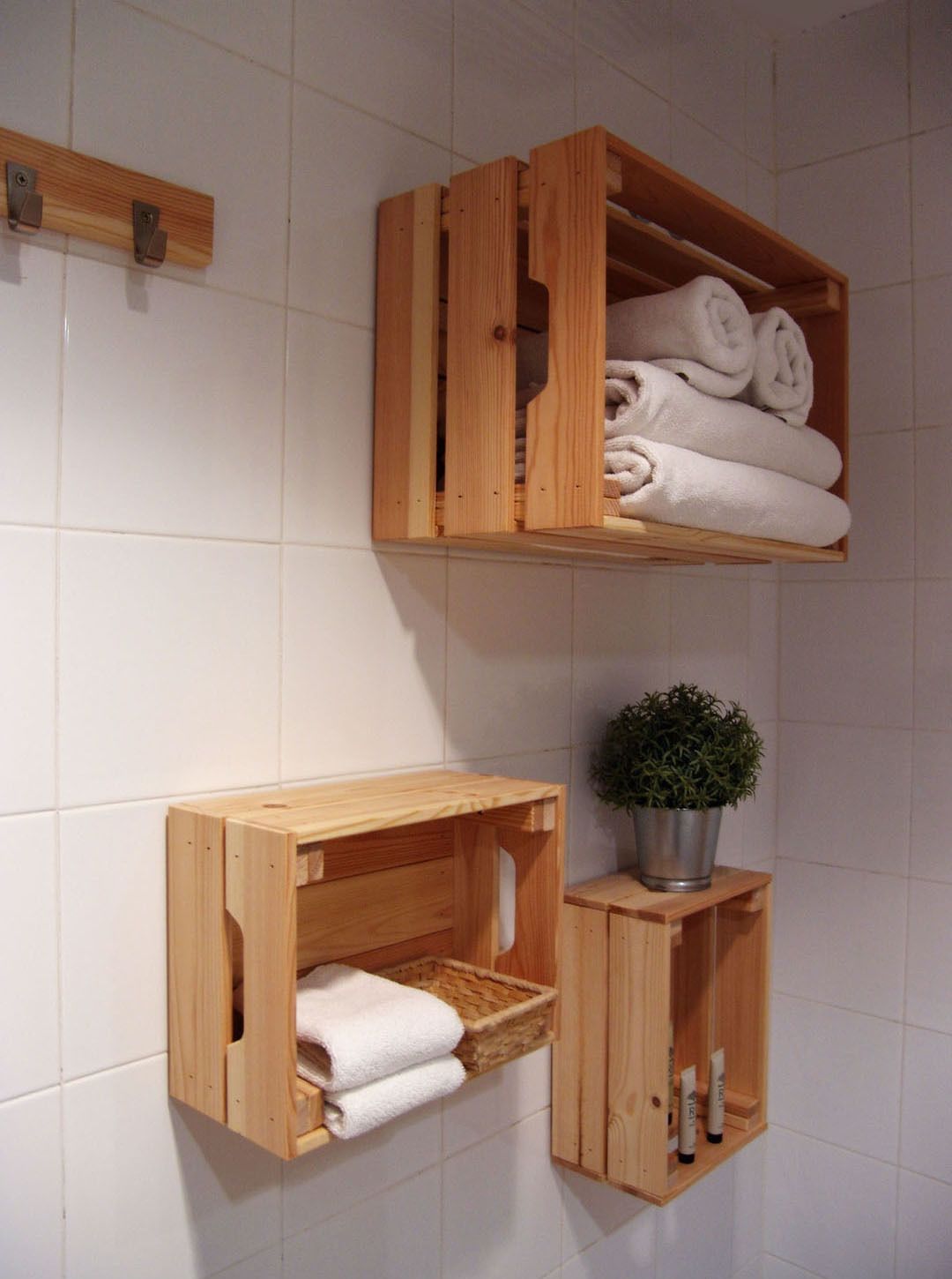 A bathroom with wooden storage shelves holding towels and toiletries.