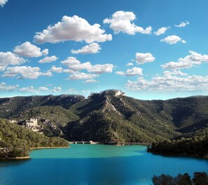 Un paysage montagneux avec un lac turquoise et un pont.