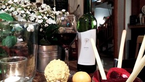A dining table with a bottle of wine, glasses, a bowl of fruit, and a decorative plant. - Hotel La Tinensa (La Pobla de Benifassa)