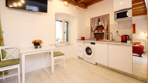 A compact kitchen with a washing machine, a microwave, and a dining area with a table and chairs. - Melek Accommodations (Dubrovnik)