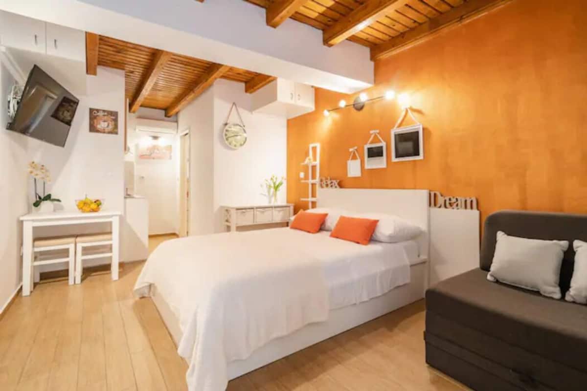 A bedroom with a bed, a bedside table, a dresser, and a sofa.