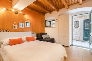 A bedroom with a large bed, a wardrobe, and a small seating area.
