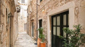 A narrow stone alleyway with a door and potted plants. - Melek Accommodations (Dubrovnik)