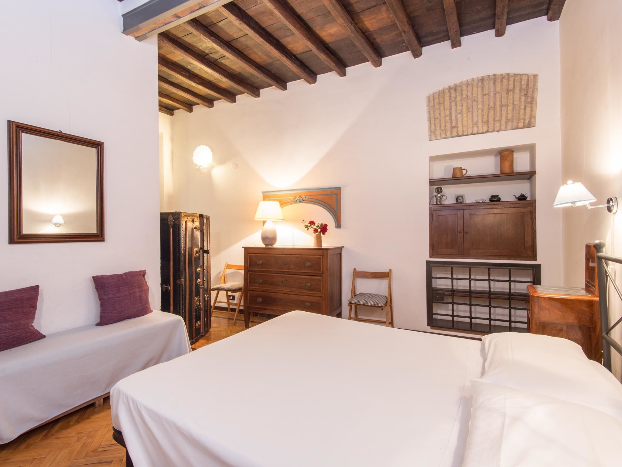 Un dormitorio con dos camas, un tocador, una silla, una lámpara y un espejo.