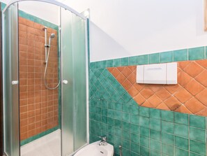 A bathroom with a glass shower enclosure, a sink, and a toilet.