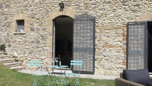 A stone building with a patio area featuring a table and chairs, a wicker sofa, and a stone staircase.