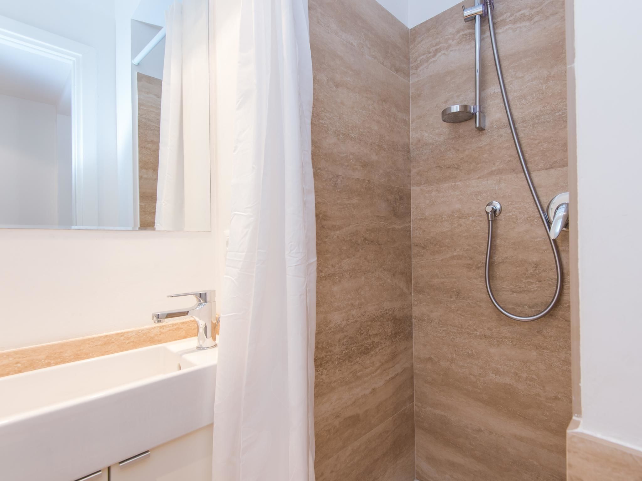 A bathroom with a shower, a sink, and a mirror.