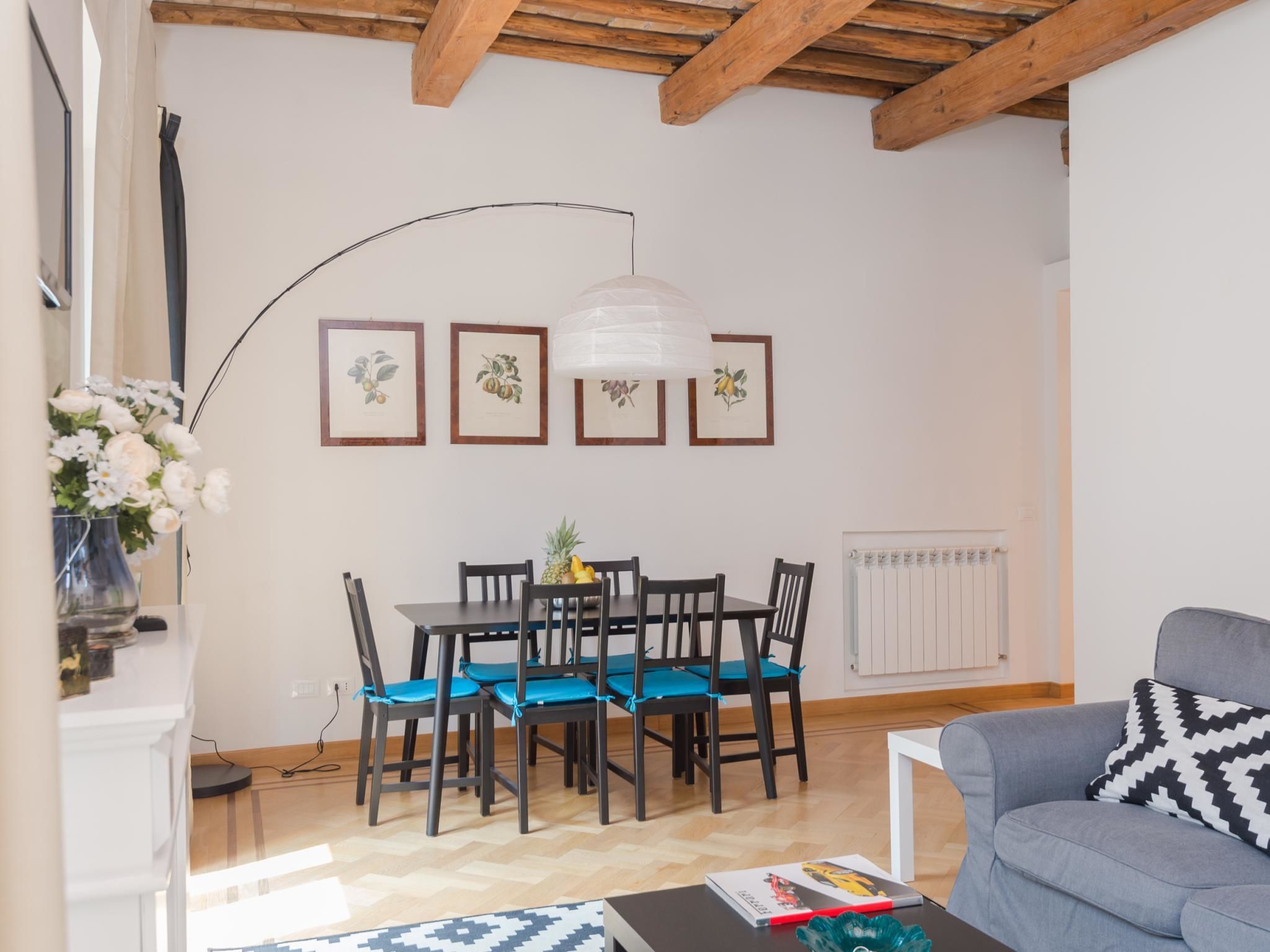 A dining area with a table and chairs, framed pictures on the wall, and a radiator.