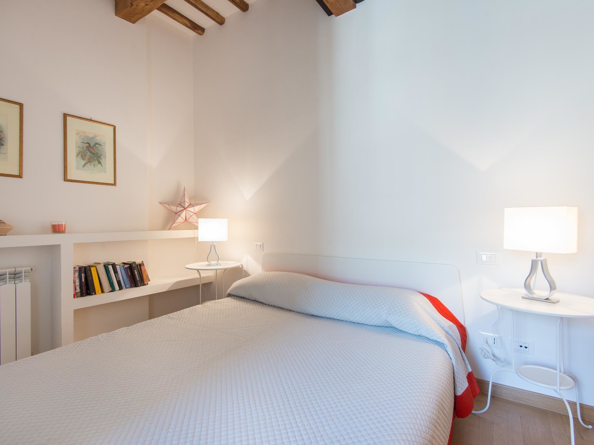A bedroom with a bed, bedside tables, a bookshelf, and a star decoration on the wall.