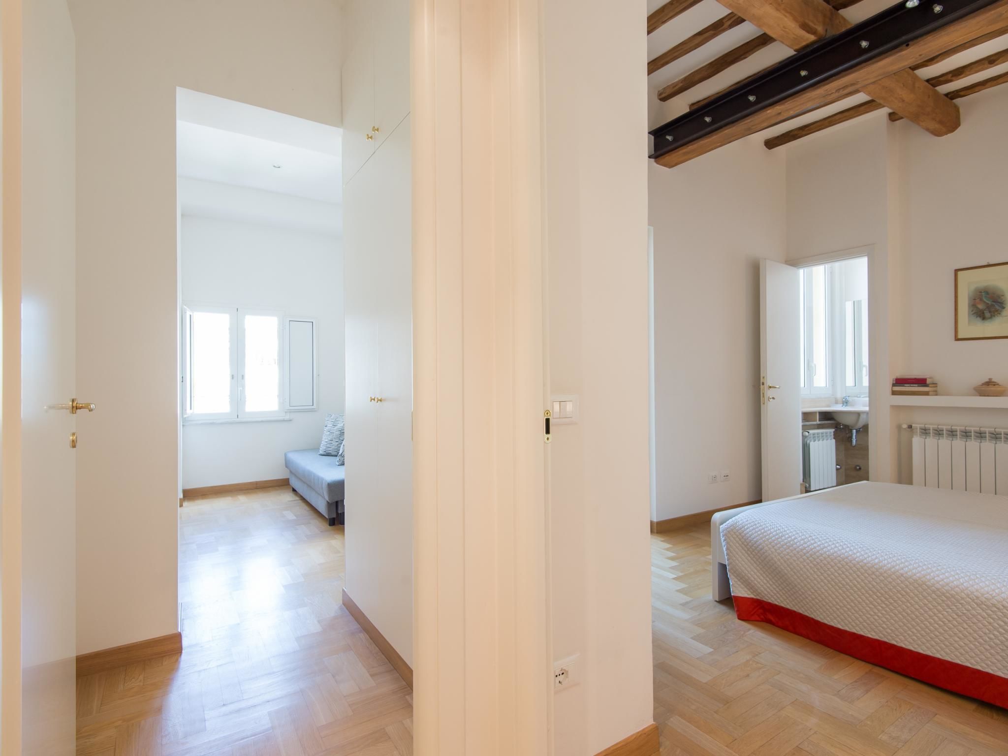 A bedroom with a bed, a window, and a bathroom visible through an open door.