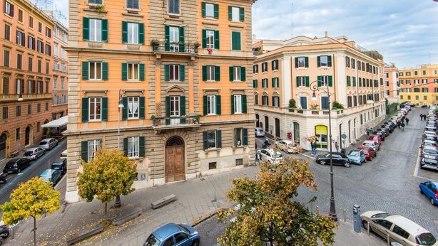 A multi-story building with a central entrance, a courtyard, and a parking area.