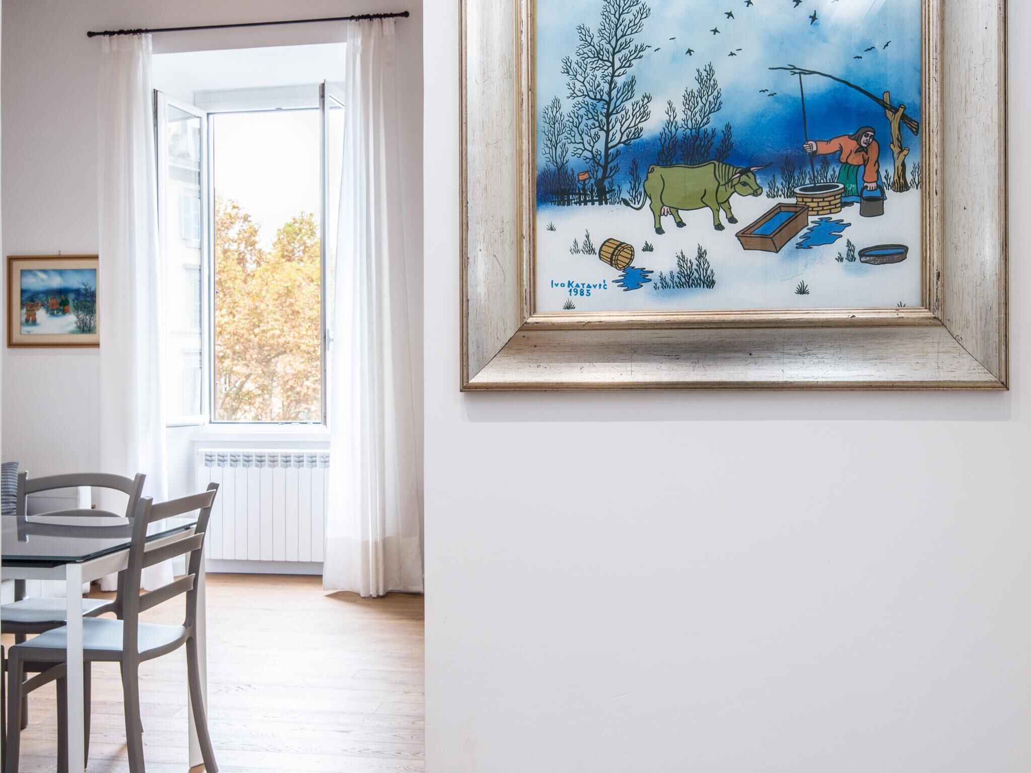 Ein Zimmer mit großem Fenster, Esstisch und Stühlen.