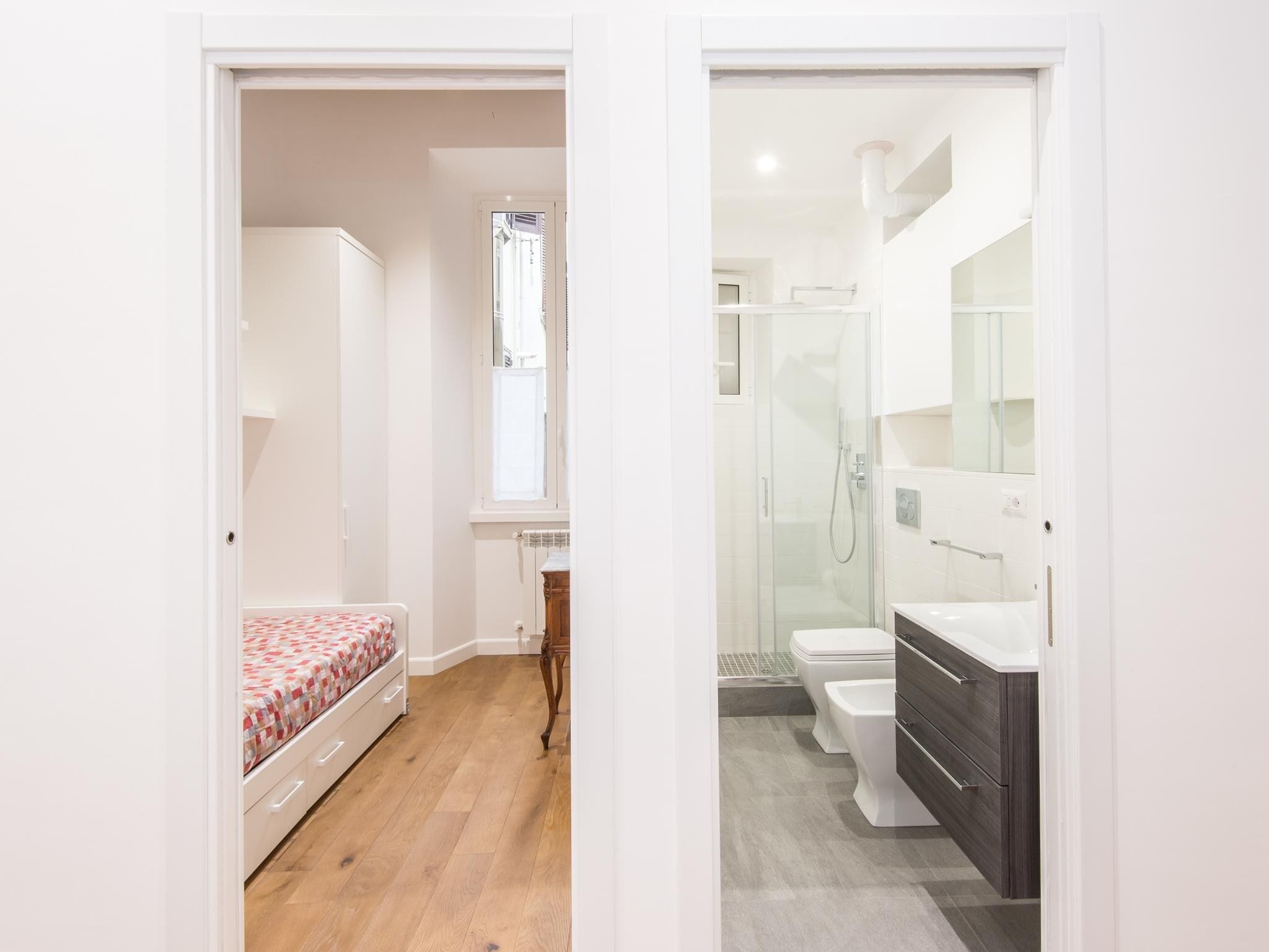 A bedroom with a bed and a bathroom with a shower and toilet.