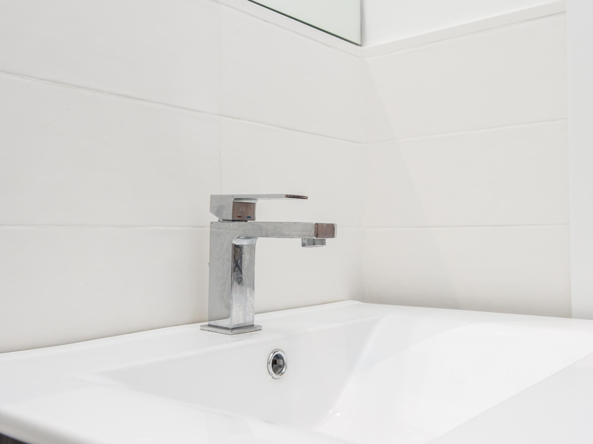 A modern bathroom with a chrome faucet and a white sink.
