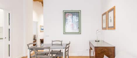 Uma sala de estar moderna com área de jantar, apresentando um sofá branco, uma mesa de jantar com cadeiras e um armário de madeira.