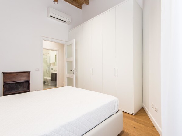 A bedroom with a bed, a wardrobe, and a bathroom visible through an open door.