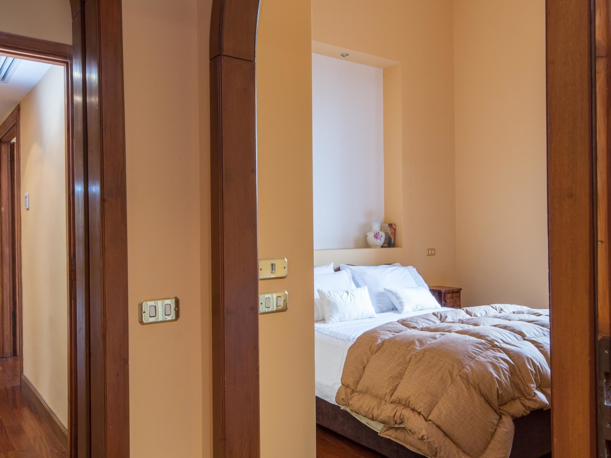 Ein Schlafzimmer mit einem Bett, Holztürrahmen und einem Lichtschalter an der Wand.