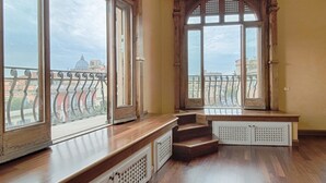 A room with large windows, wooden steps, and a view of buildings.