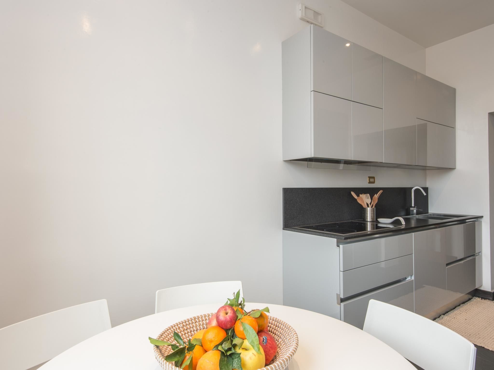 A modern kitchen with white cabinets, a black countertop, and a dining area with a white table and chairs.
