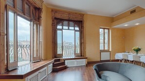 A spacious room with large windows, a dining area, and a curved grey sofa.