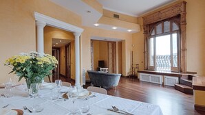 A dining area with a table set for a meal, a vase of flowers, and a view of the outdoors through a large window.