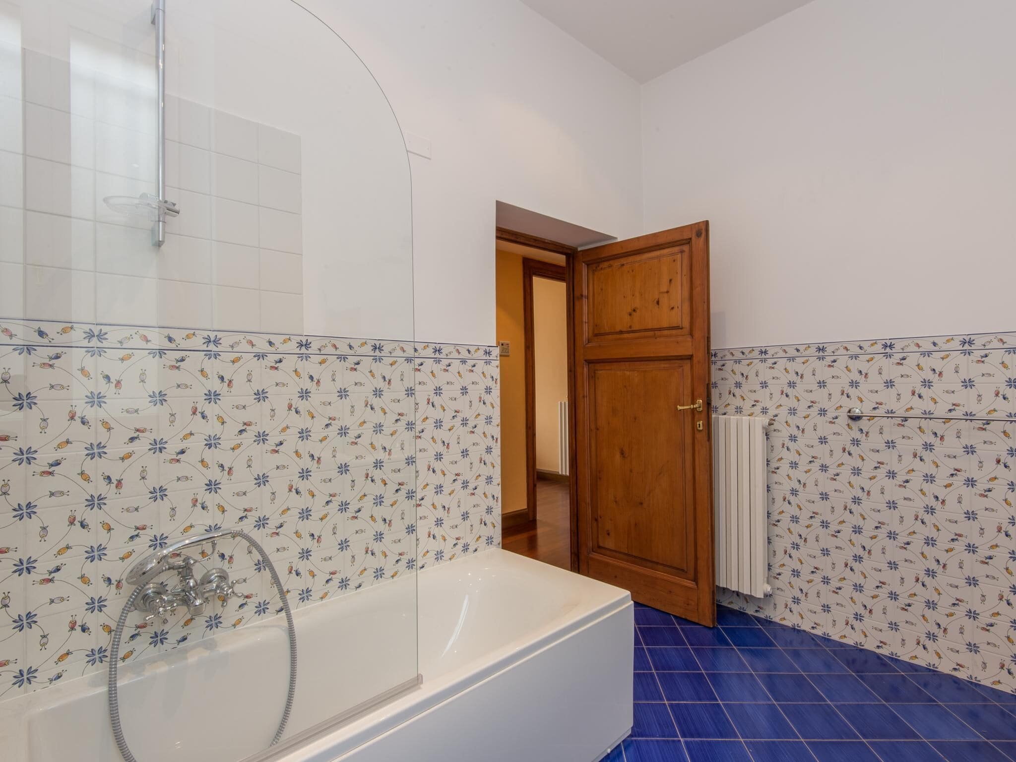Une salle de bain équipée d’une baignoire, d’une douche et d’une porte donnant sur une autre pièce.