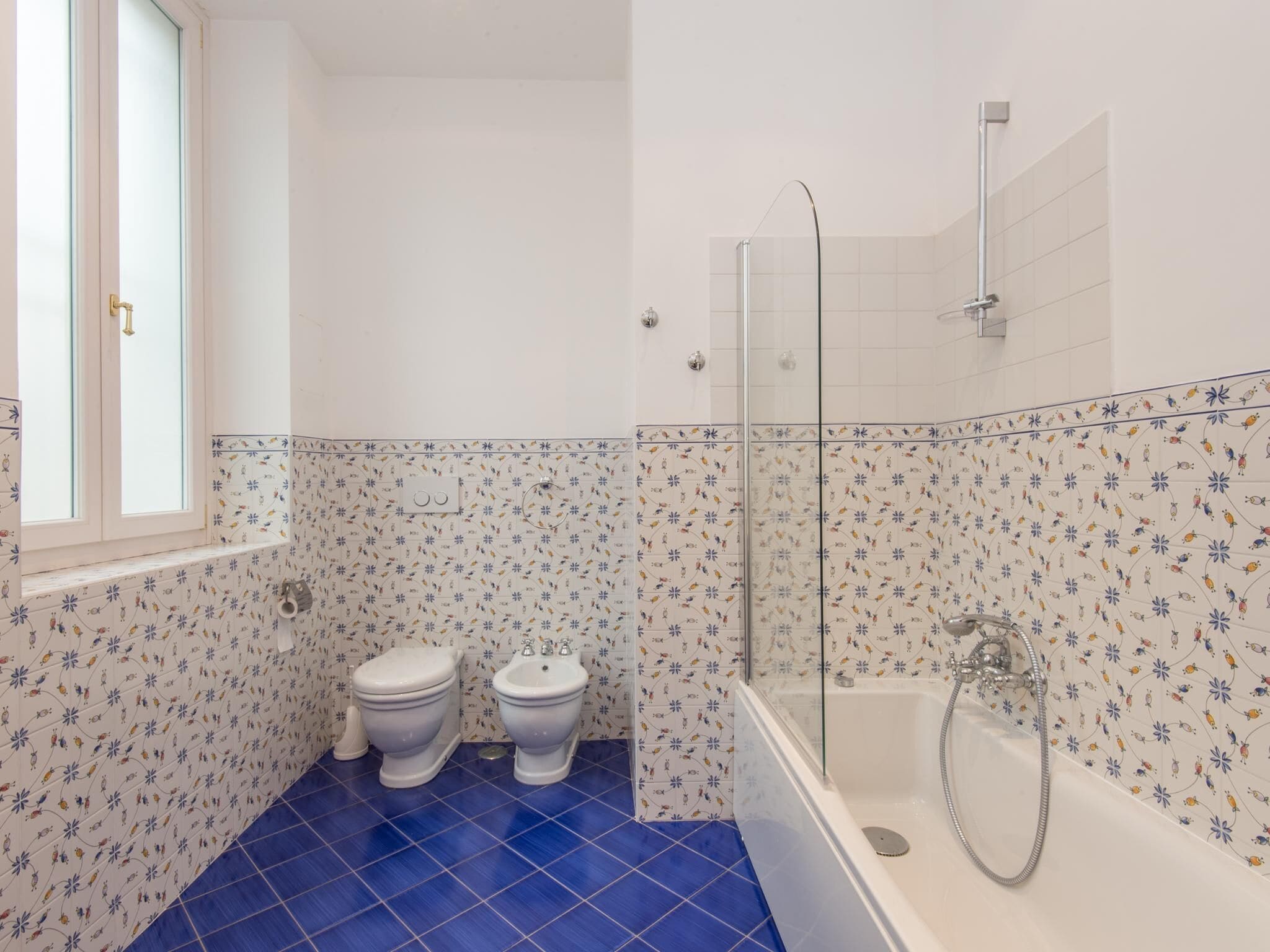 Een badkamer met twee toiletten, een bad en een douche.