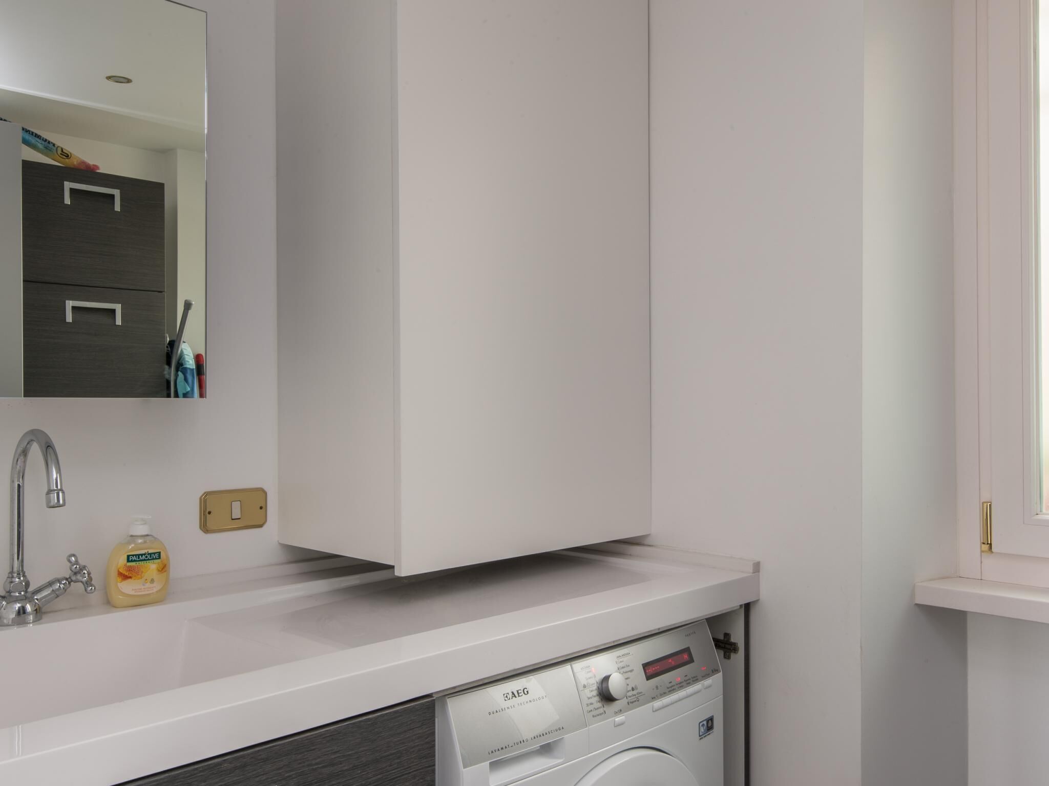 Een moderne badkamer met een ingebouwde wasmachine, een spiegel en een handdoekhouder.