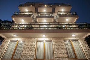 Un edificio de varios pisos con balcones, ventanas amplias y fachada de piedra.