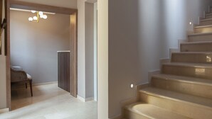 Un interior moderno con una escalera, una silla y una lámpara.