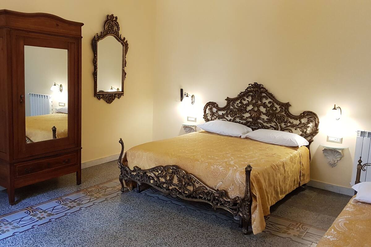Un dormitorio con un armario de madera grande, una cama ornamentada con edredón dorado y un espejo en la pared.