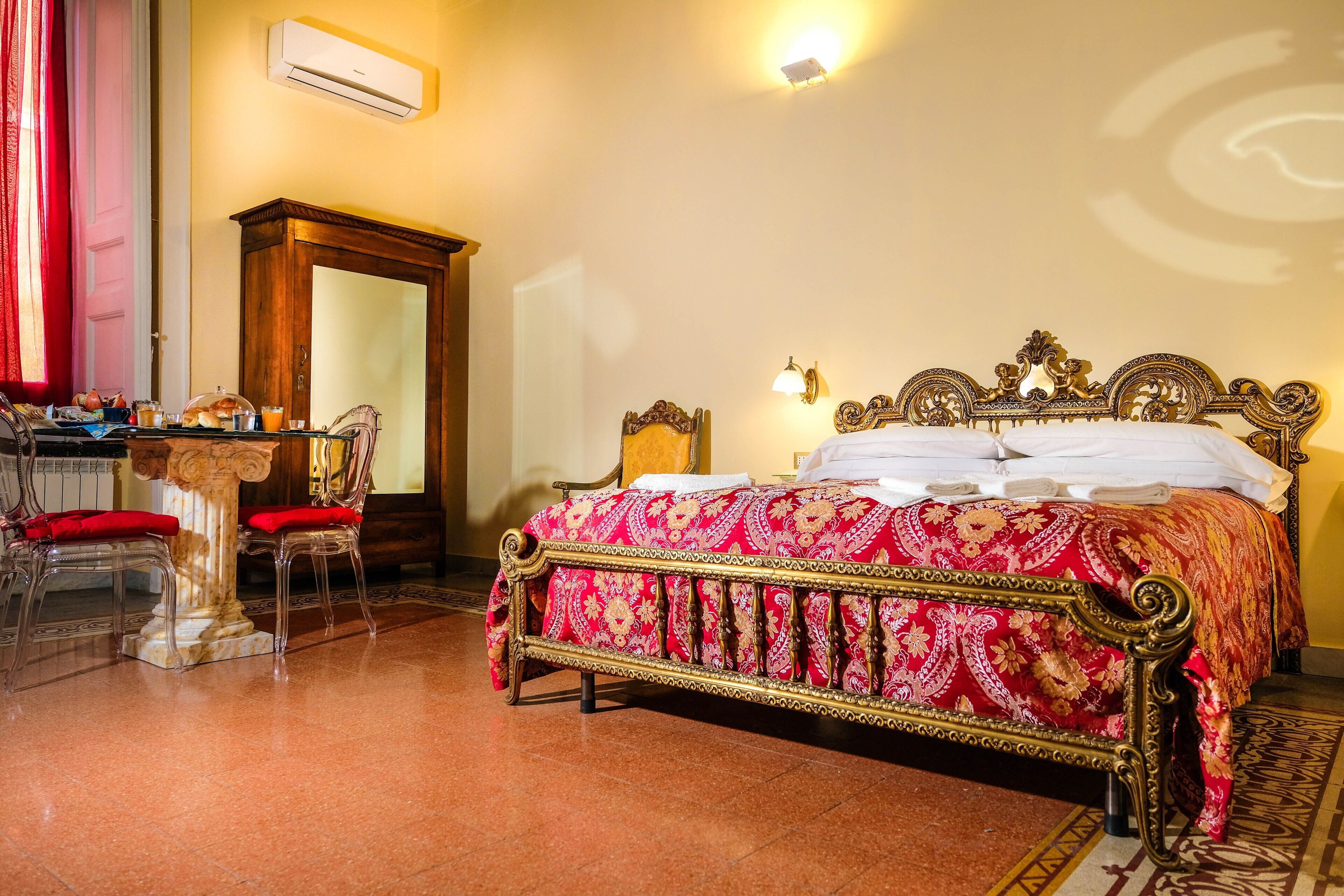 Una habitación con una cama grande, un armario de madera, un escritorio con sillas y un espejo.
