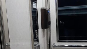 Un ascenseur moderne doté d’un écran numérique, d’une finition métallique et d’une porte en verre.