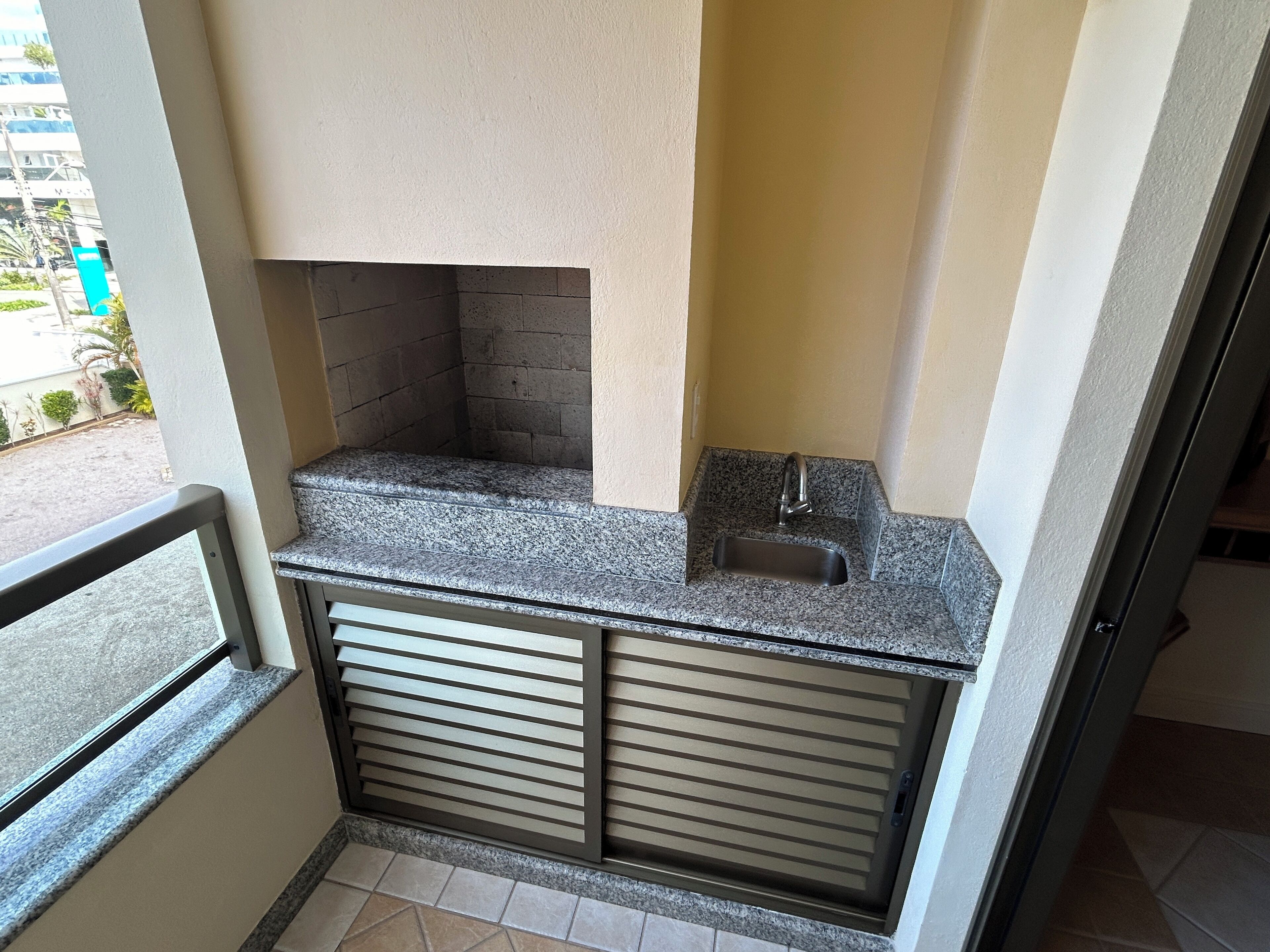 A small kitchen area with a sink, a window, and a view of a building outside.