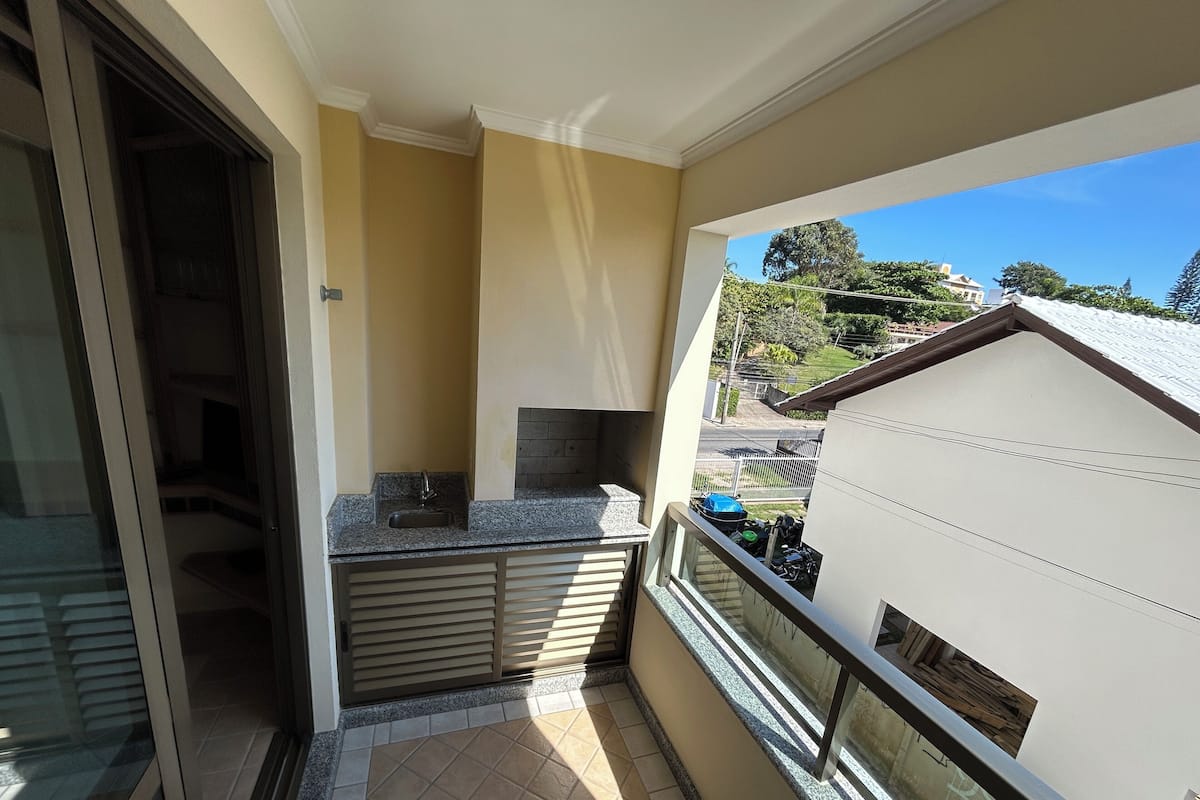 A balcony with a sink, a window, and a view of the neighborhood.