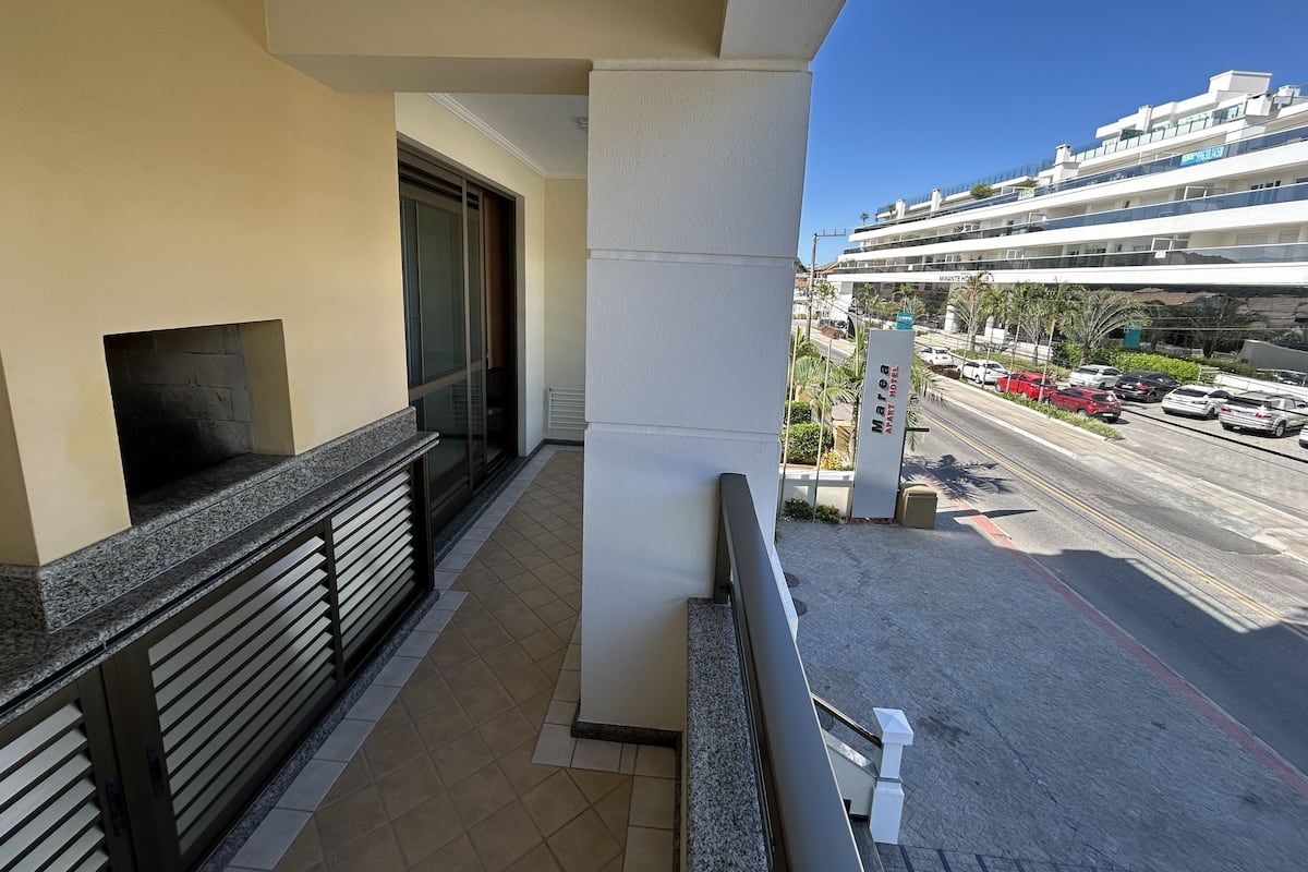 A hotel balcony with a view of a busy street and a cruise ship in the background.