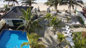 Un complexe hôtelier doté d’une piscine, de palmiers et offrant une vue sur la plage.