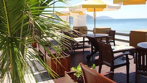 Un espace extérieur aménagé avec des tables, des chaises, des parasols et une vue sur la mer.