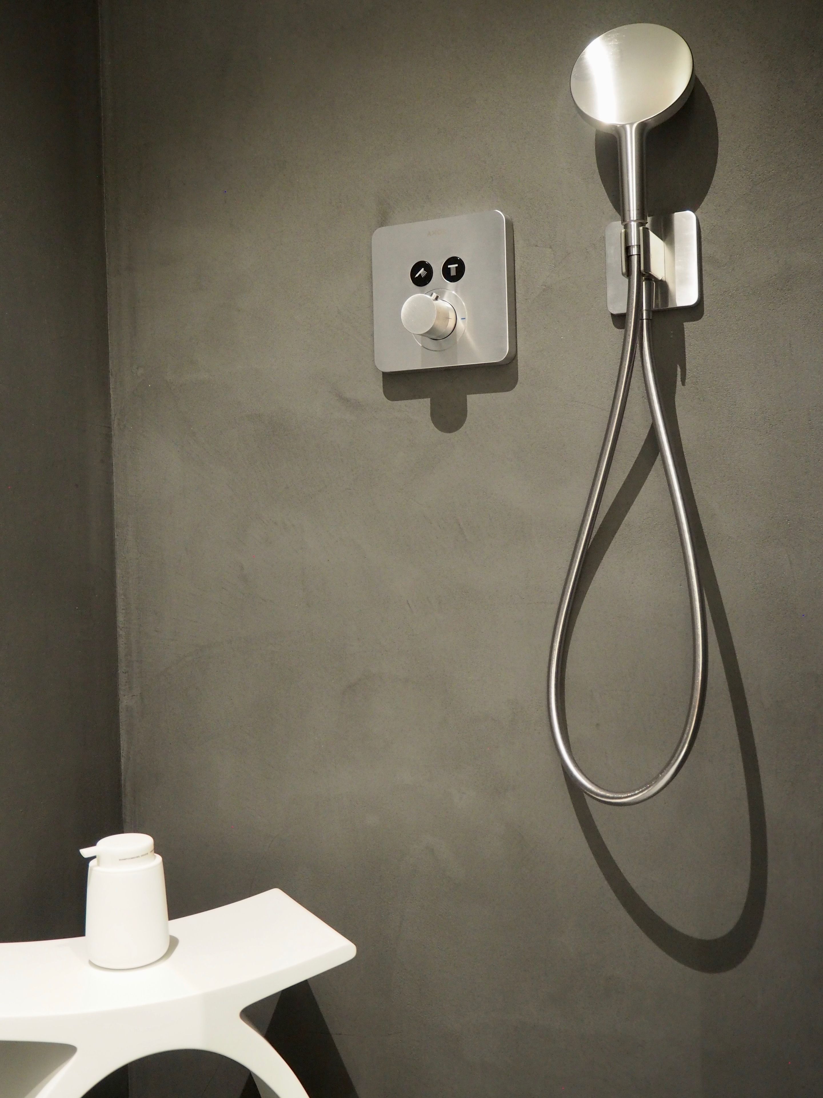 Un baño moderno con ducha, panel de control y un lavabo blanco.