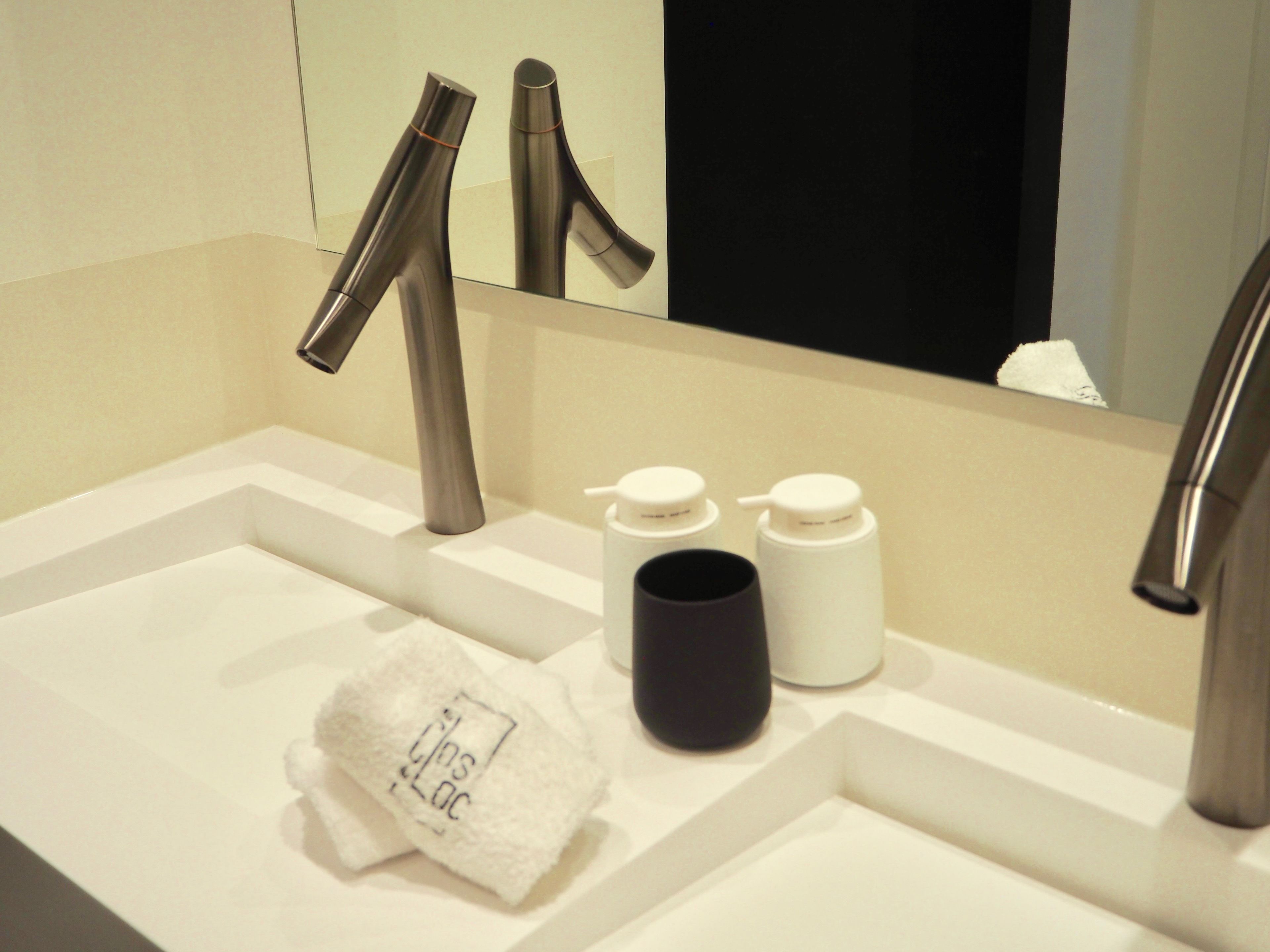 Une salle de bain moderne avec un lavabo blanc, deux robinets et un miroir.