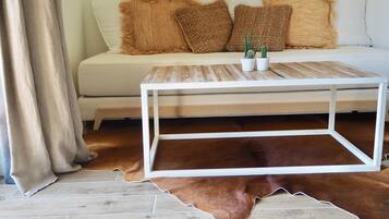 Une pièce avec un canapé blanc, des coussins marron et beige, une table basse blanche et un tapis en cuir marron.